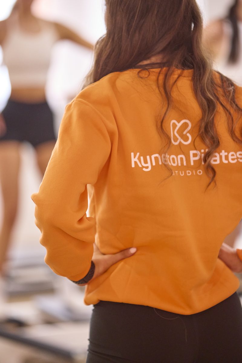 Kyneton Pilates instructor in branded orange jumper